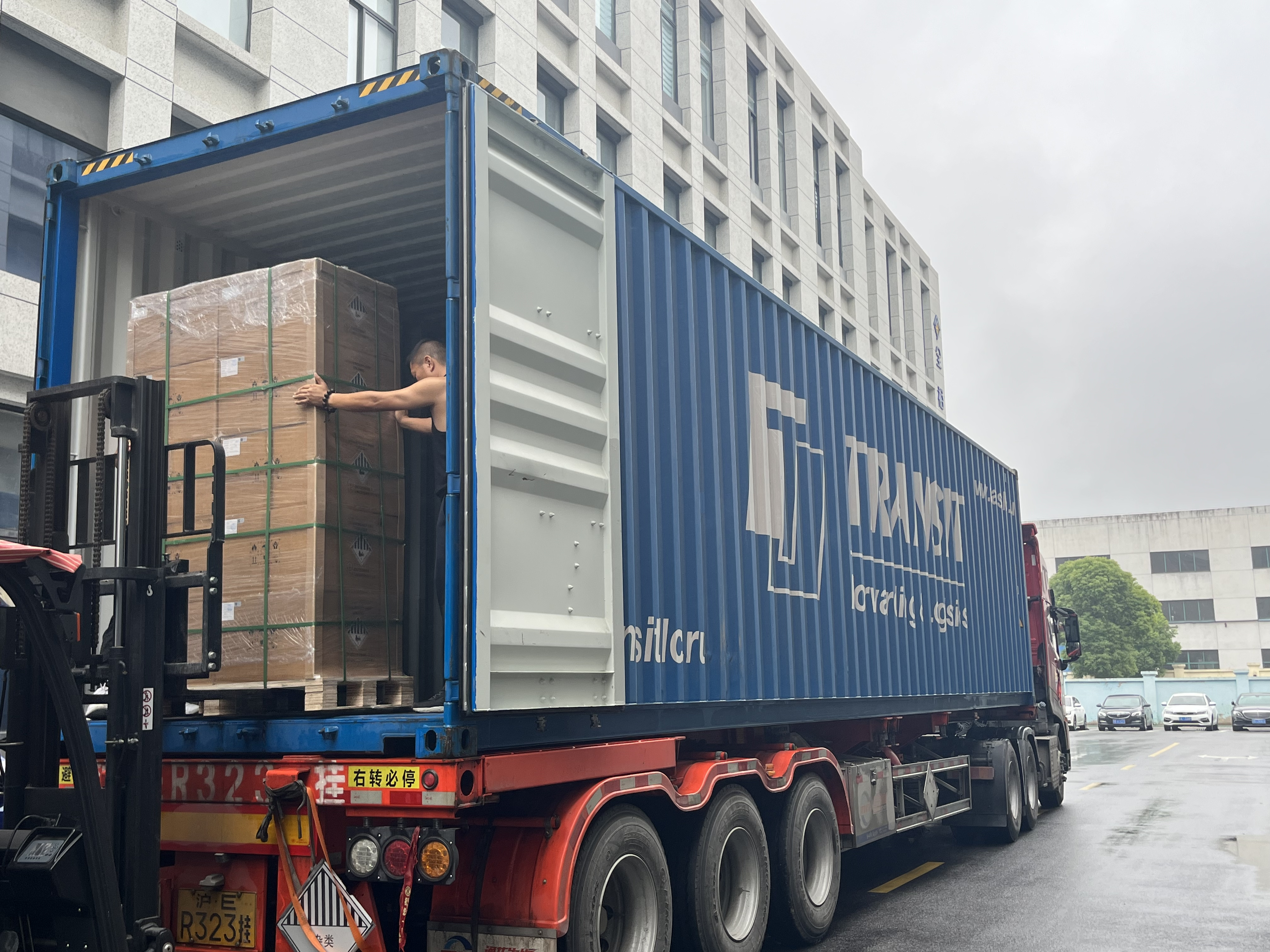 Forklift loading packaged floor-cleaning equipment into an export container